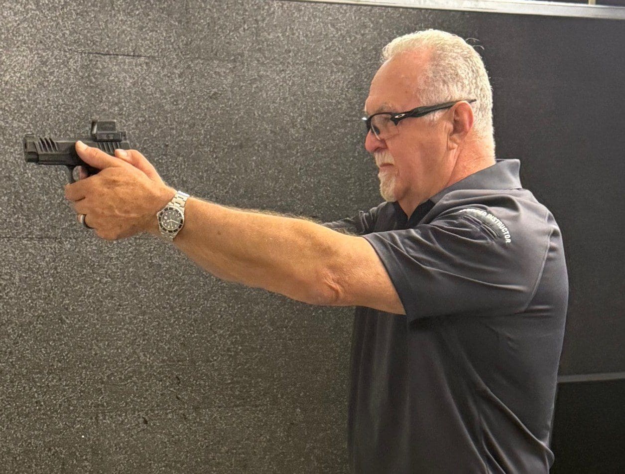 Man aiming a handgun at a shooting range.