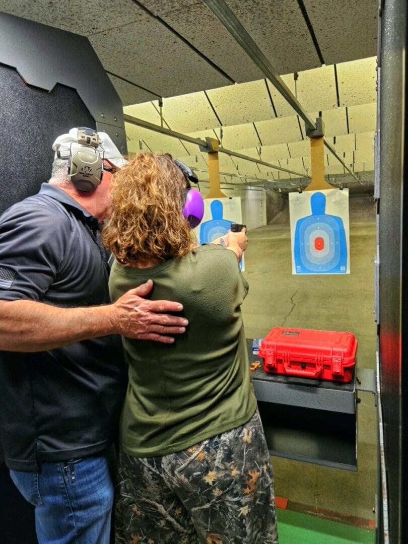 Two people at a shooting range aiming at a target.