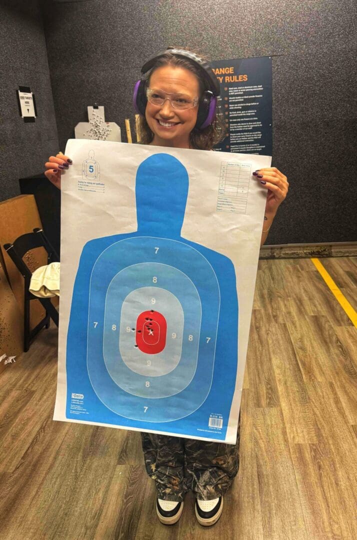 Person holding a colorful shooting target with bullet holes.