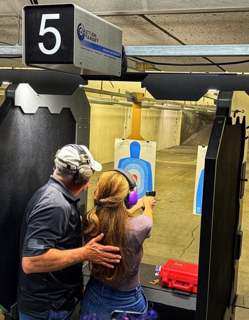Instructor guiding young woman at indoor shooting range.