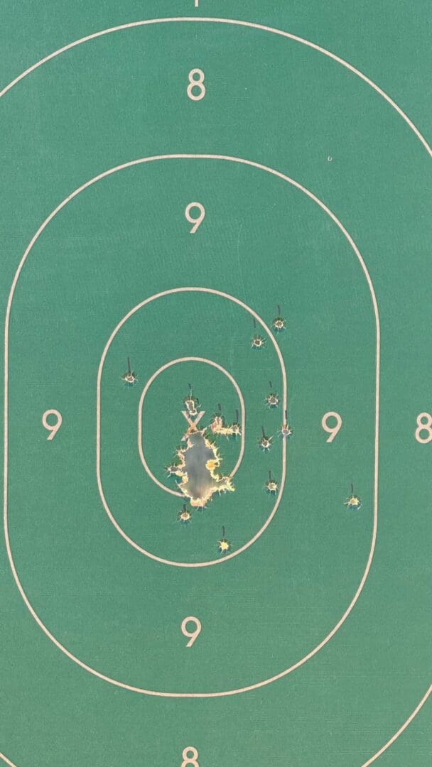 A paper shooting target with multiple bullet holes clustered near the center.