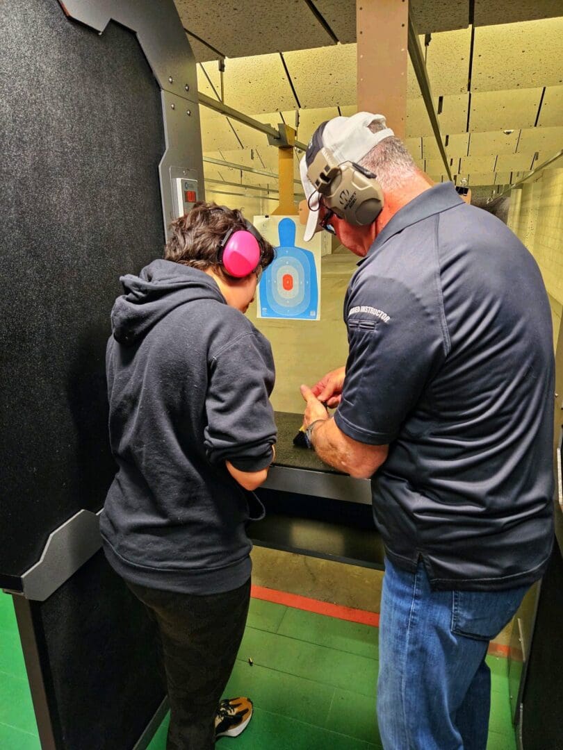 Two people at a shooting range aiming at a target.