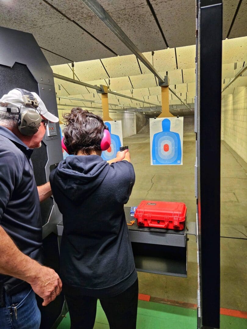 Person receiving firearm training at an indoor shooting range with an instructor.