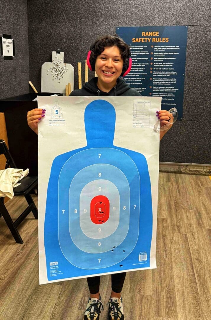 Person holding a paper target with bullet holes.
