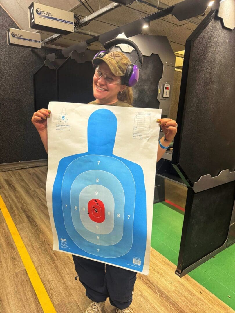 A young person smiling while holding a colorful target poster.