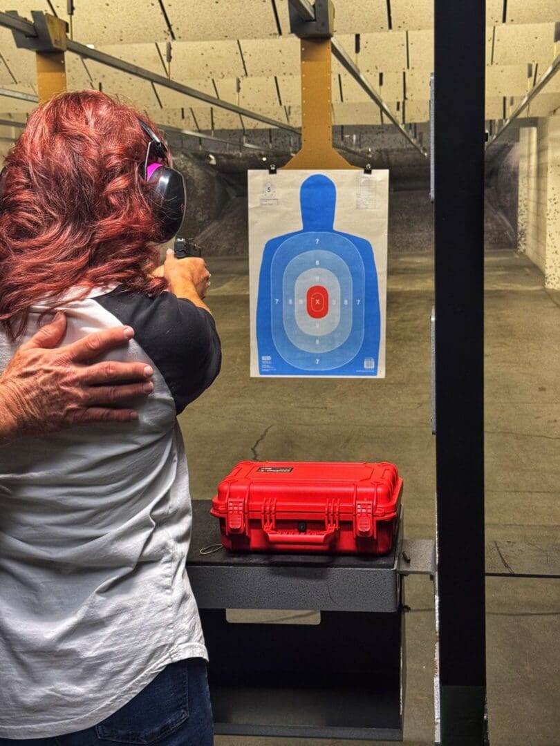 A person aims at a paper target in an indoor shooting range.