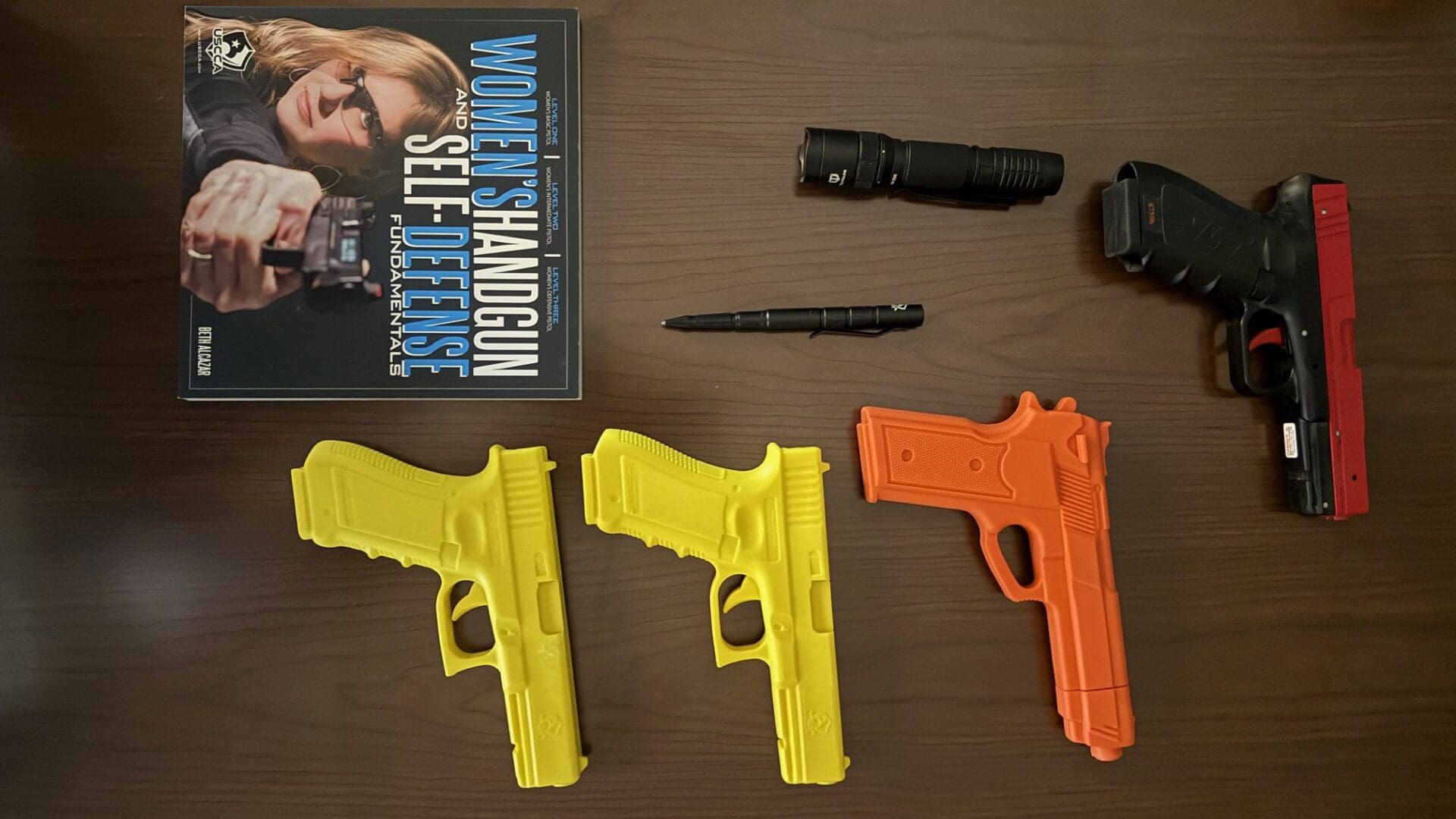 Three colorful toy guns and accessories on a wooden surface.