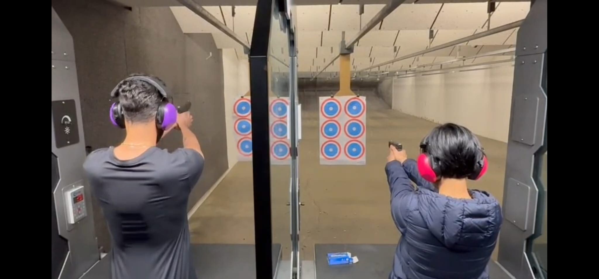 Two people shooting at indoor gun range.