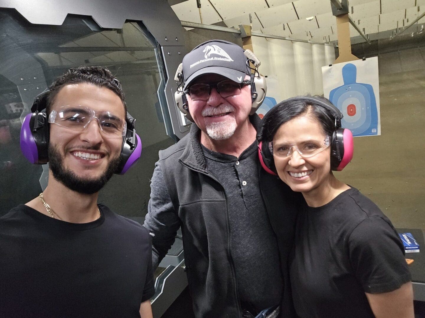 Three people smiling at a shooting range.
