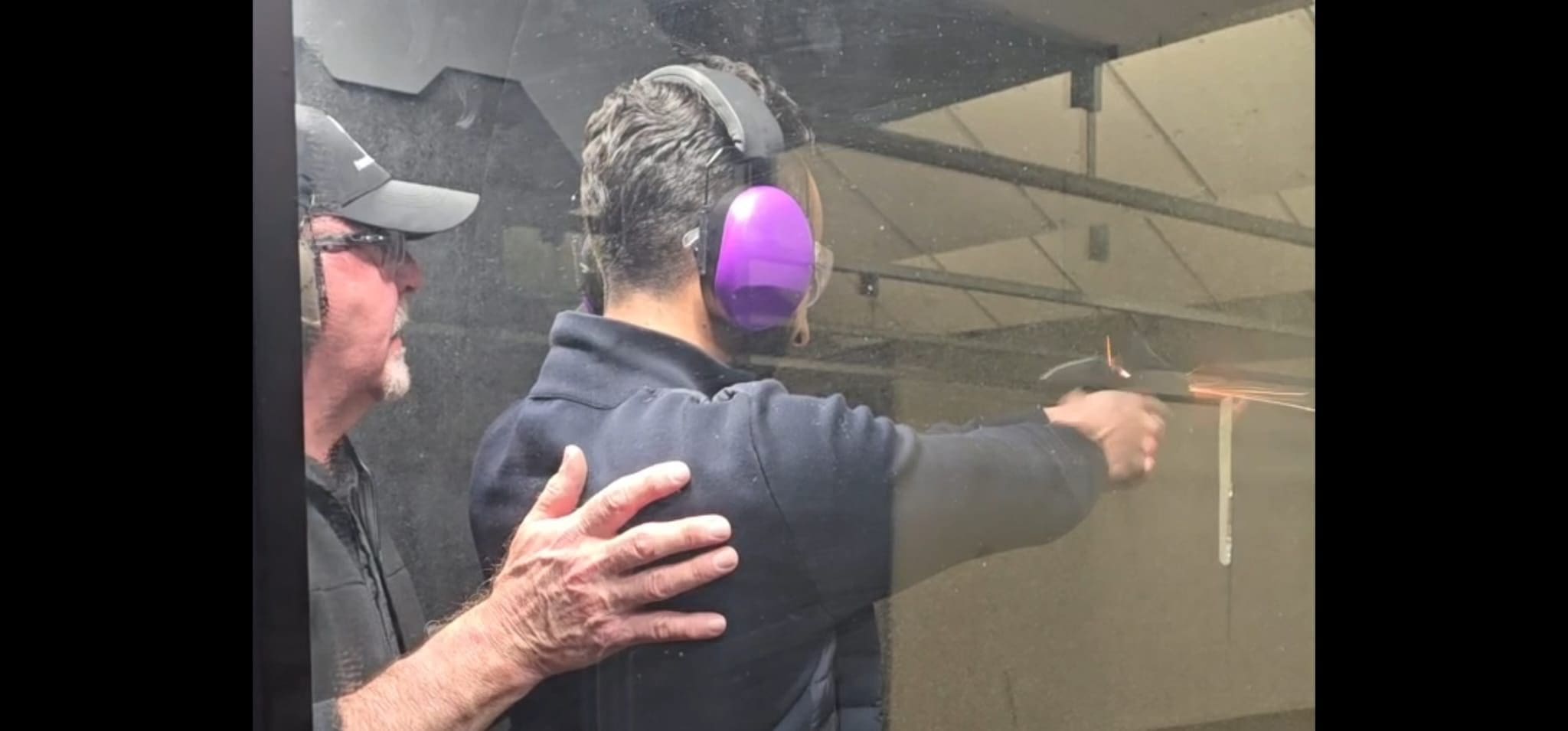 Person receiving shooting instruction at gun range.
