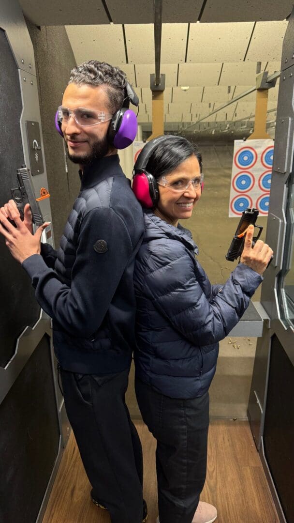 Two people back-to-back at shooting range.