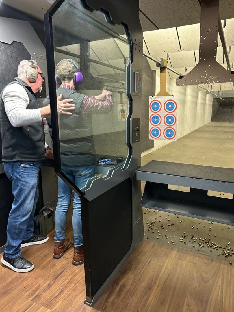 Indoor shooting range with two people practicing.