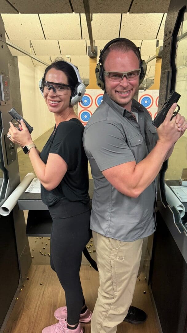 Two people posing with guns at range.