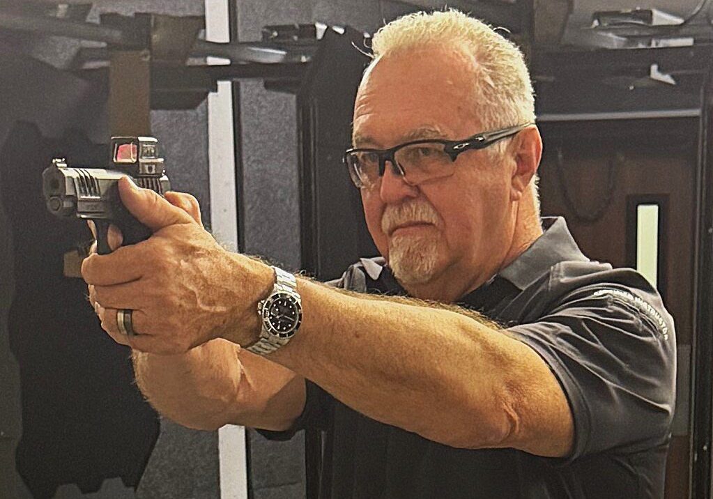 Man aiming a handgun with focused expression indoors.